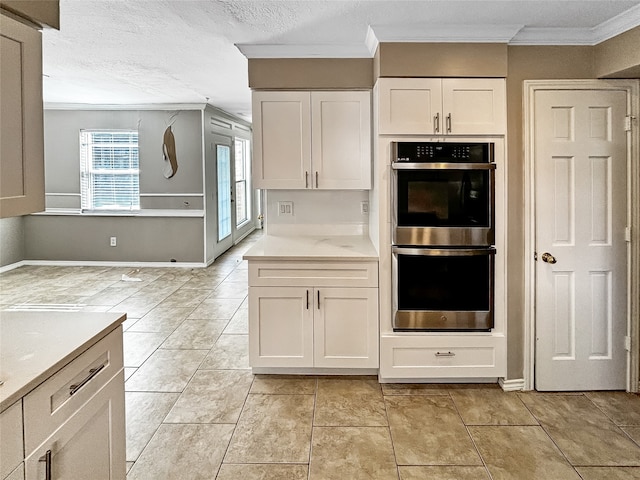 kitchen with white cabinets, a textured ceiling, stainless steel double oven, and crown molding