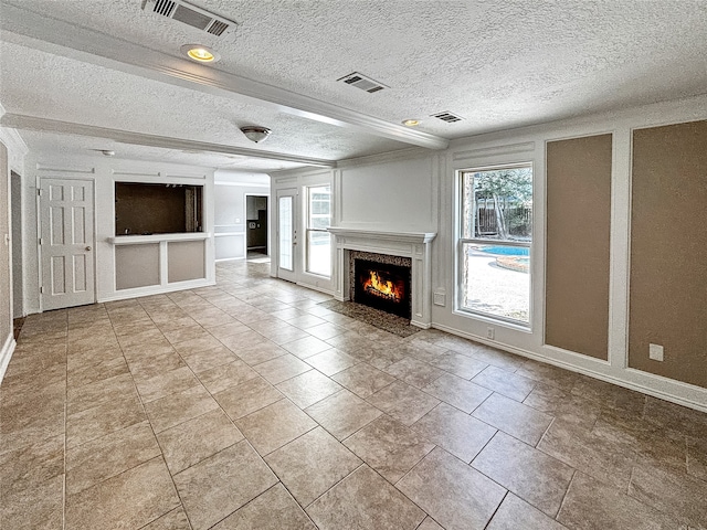 unfurnished living room with built in shelves, a wealth of natural light, light tile patterned floors, and a textured ceiling