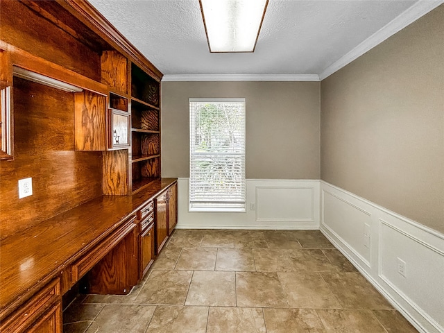 unfurnished office with a textured ceiling, built in desk, and ornamental molding