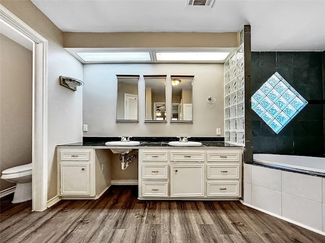 1519 Hannington Dr, Katy, TX 77450 - bathroom with wood finished floors, tiled bath, a sink, and toilet
