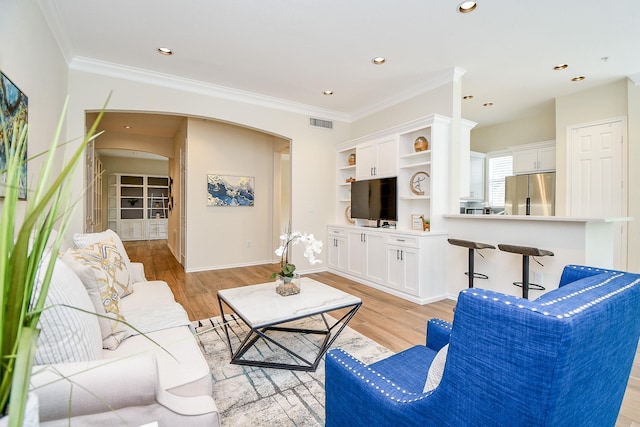 living room with light hardwood / wood-style floors, built in features, and crown molding