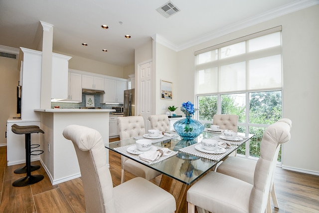 dining room with hardwood / wood-style flooring, a wealth of natural light, and crown molding