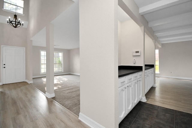 foyer featuring hardwood / wood-style floors, plenty of natural light, beam ceiling, and a notable chandelier