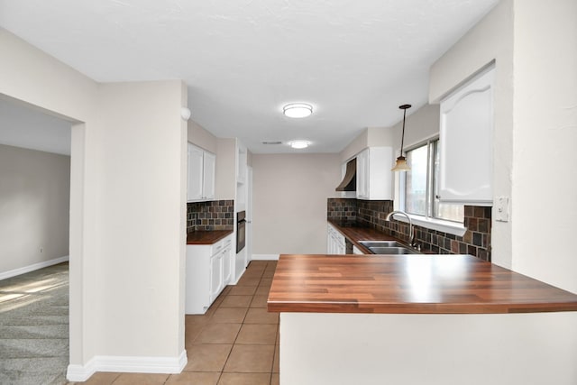 kitchen with decorative backsplash, decorative light fixtures, butcher block counters, and sink