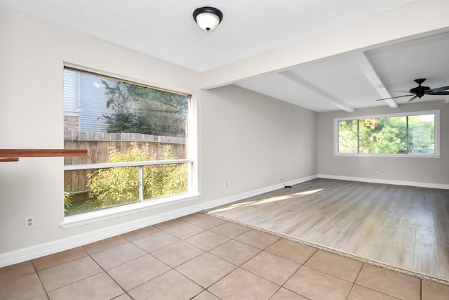 empty room with beam ceiling, light wood-type flooring, and ceiling fan