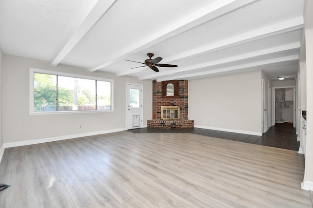 unfurnished living room featuring ceiling fan, beam ceiling, light wood-type flooring, and a fireplace