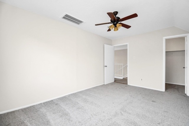 unfurnished bedroom featuring carpet, lofted ceiling, ceiling fan, a spacious closet, and a closet