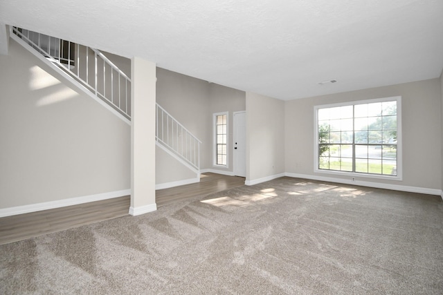 unfurnished living room with dark colored carpet and a textured ceiling