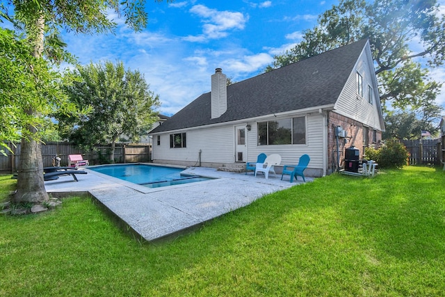 rear view of house with a lawn, a patio area, and a fenced in pool