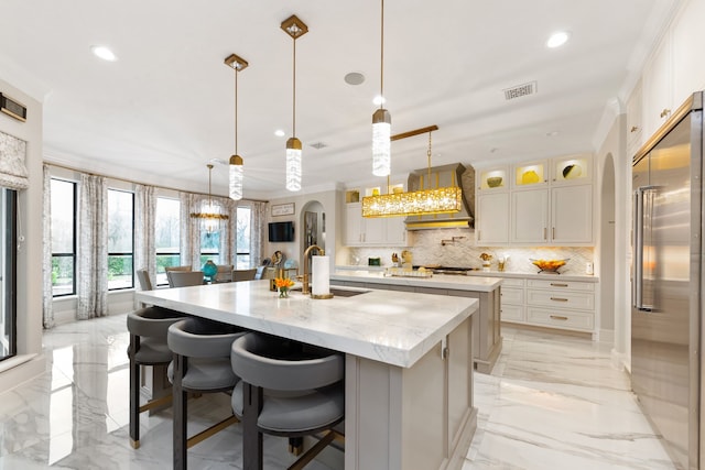 kitchen featuring pendant lighting, backsplash, a kitchen island with sink, and appliances with stainless steel finishes