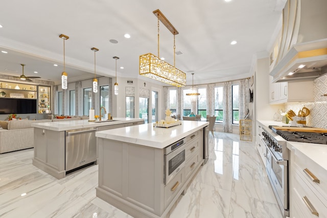 kitchen featuring sink, hanging light fixtures, appliances with stainless steel finishes, a large island, and custom range hood