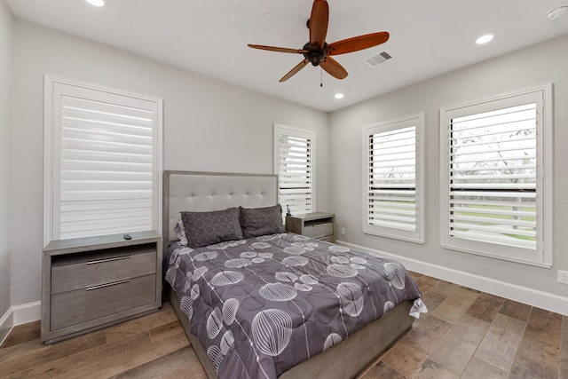 bedroom with multiple windows, wood-type flooring, and ceiling fan