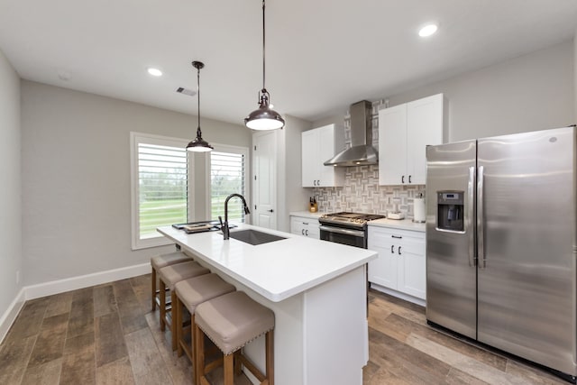 kitchen featuring a kitchen island with sink, sink, wall chimney exhaust hood, dark hardwood / wood-style floors, and stainless steel appliances