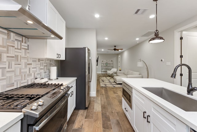 kitchen featuring sink, stainless steel appliances, dark hardwood / wood-style floors, pendant lighting, and extractor fan