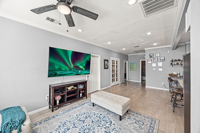 living room with hardwood / wood-style floors, a textured ceiling, ceiling fan, and ornamental molding