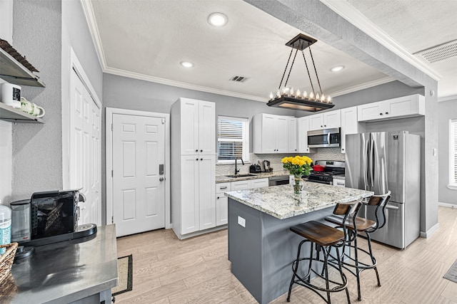 kitchen with white cabinets, pendant lighting, stainless steel appliances, and ornamental molding