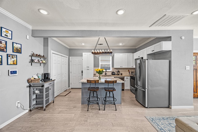 kitchen with appliances with stainless steel finishes, light wood-type flooring, a breakfast bar, white cabinets, and a center island