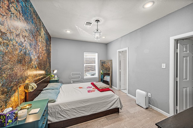 bedroom featuring light hardwood / wood-style floors and a textured ceiling