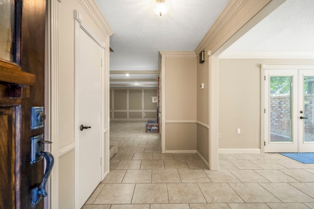 hall featuring light tile patterned floors, a textured ceiling, french doors, and ornamental molding