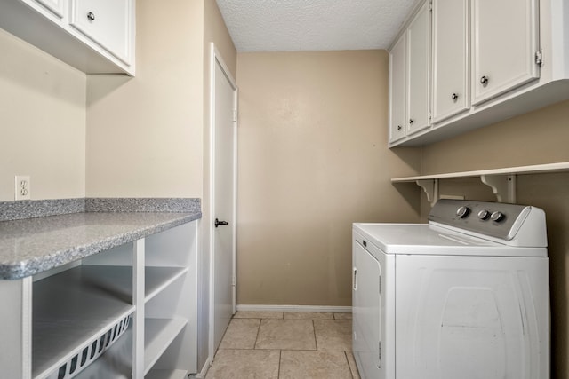 laundry area featuring light tile patterned floors, cabinets, a textured ceiling, and washer / dryer