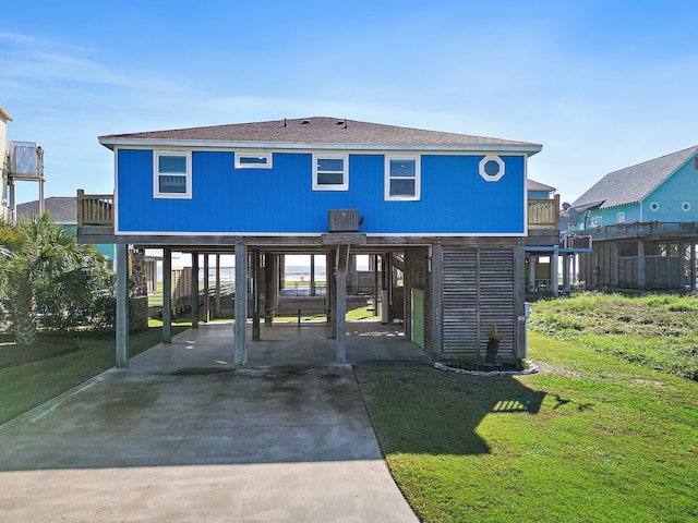 back of property featuring a carport, cooling unit, and a lawn