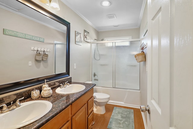 full bathroom with vanity, combined bath / shower with glass door, crown molding, toilet, and wood-type flooring