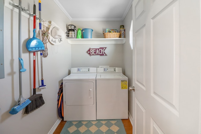 clothes washing area with light wood-type flooring, washer and clothes dryer, and ornamental molding