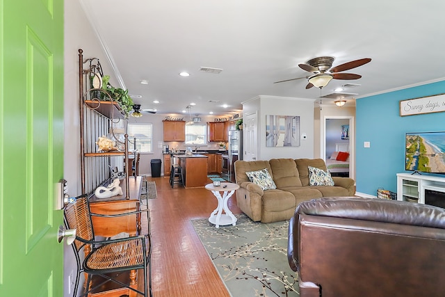 living room featuring ceiling fan, wood-type flooring, and ornamental molding