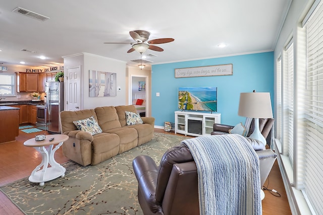 living room featuring crown molding, ceiling fan, and light wood-type flooring