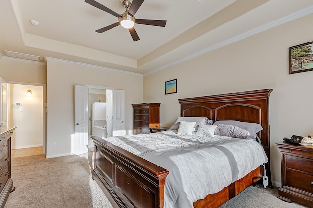 bedroom with a tray ceiling, ensuite bathroom, ceiling fan, and light carpet