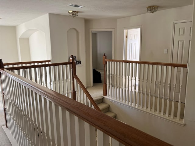 hallway featuring light colored carpet and a textured ceiling