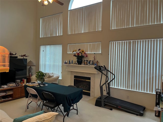 interior space with ceiling fan, a towering ceiling, and a fireplace