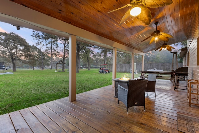 deck at dusk featuring a yard and grilling area