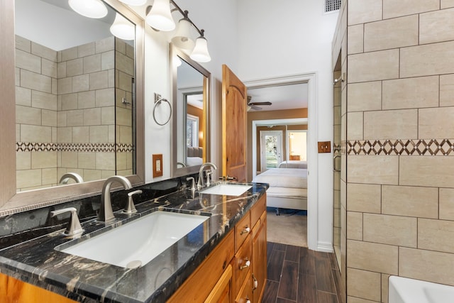 bathroom with a tile shower, ceiling fan, and vanity