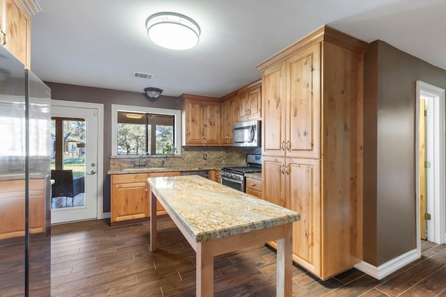 kitchen with sink, decorative backsplash, light stone countertops, appliances with stainless steel finishes, and dark hardwood / wood-style flooring