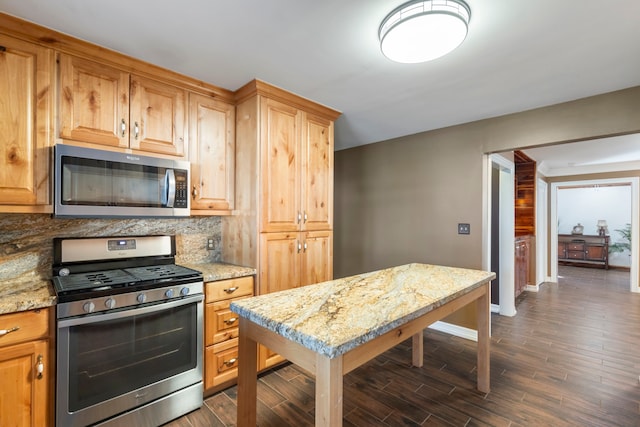 kitchen featuring backsplash, light stone countertops, dark hardwood / wood-style floors, and appliances with stainless steel finishes