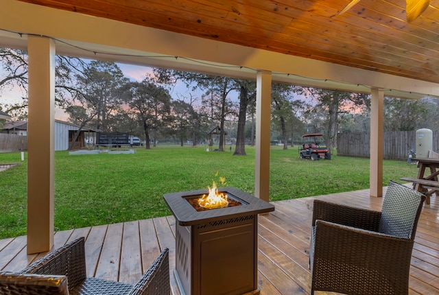 deck at dusk featuring a fire pit and a lawn