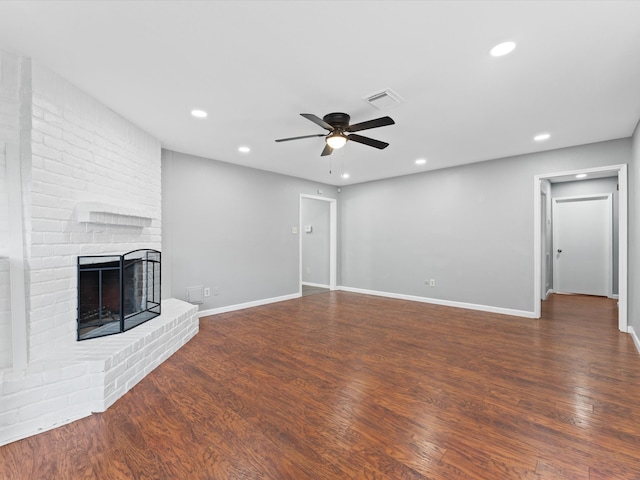 unfurnished living room with ceiling fan, a fireplace, and dark wood-type flooring