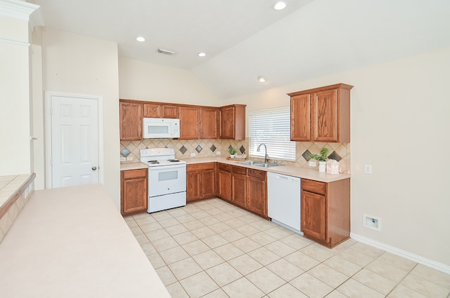 kitchen with decorative backsplash, white appliances, sink, light tile patterned floors, and lofted ceiling