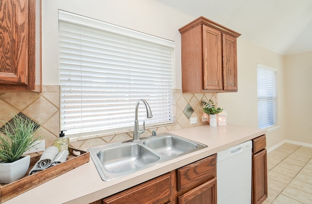 kitchen with tasteful backsplash, sink, white dishwasher, and light tile patterned floors