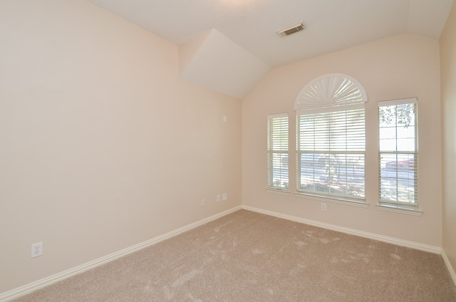 carpeted spare room featuring vaulted ceiling