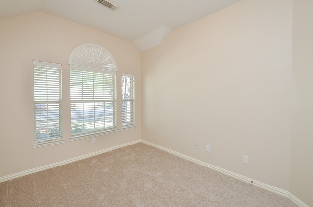 carpeted spare room featuring vaulted ceiling