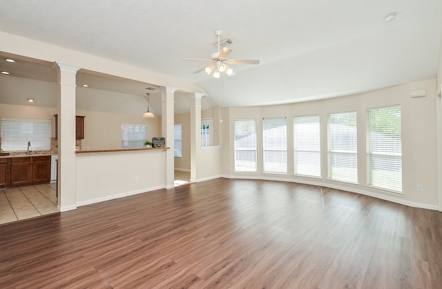 unfurnished living room with lofted ceiling, sink, ceiling fan, wood-type flooring, and decorative columns