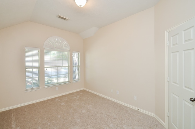 carpeted empty room featuring vaulted ceiling