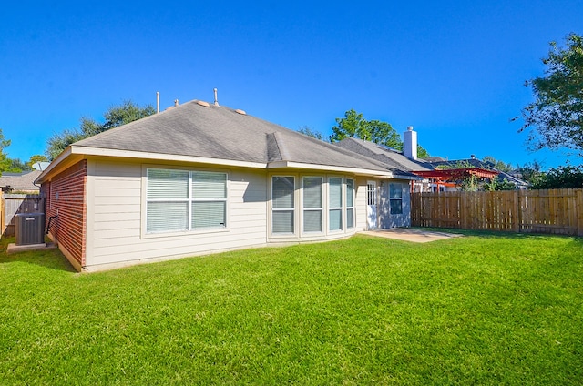 rear view of property with a lawn, cooling unit, and a patio area