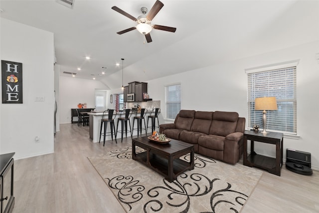 living room with light hardwood / wood-style floors, ceiling fan, and lofted ceiling