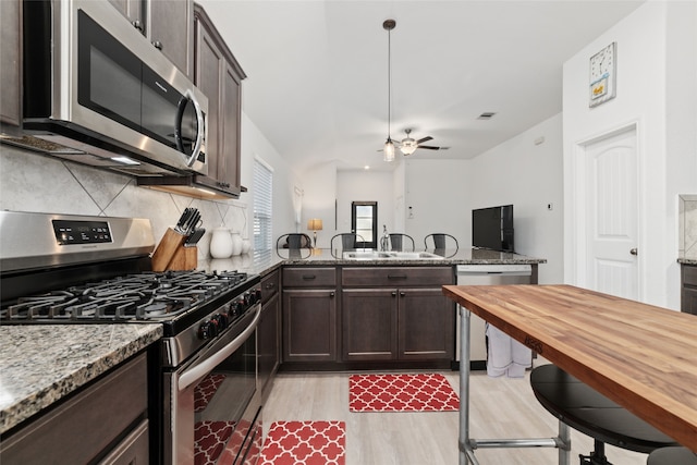 kitchen with ceiling fan, light wood-type flooring, tasteful backsplash, light stone counters, and stainless steel appliances