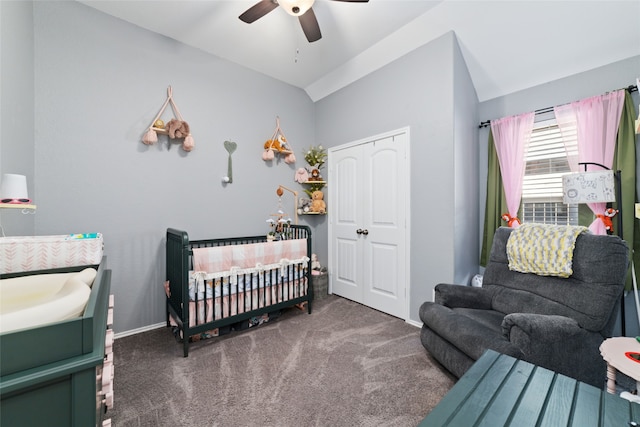 bedroom featuring dark carpet, vaulted ceiling, ceiling fan, a crib, and a closet