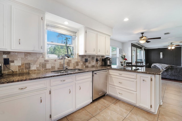 kitchen with kitchen peninsula, white cabinets, stainless steel dishwasher, and a healthy amount of sunlight