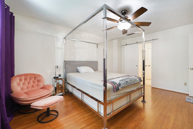 bedroom featuring ceiling fan, wood-type flooring, and a textured ceiling